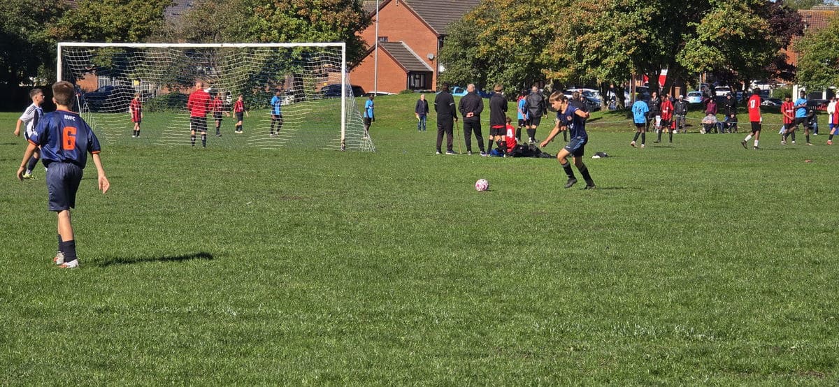 Youth football match at Rushall Village Football Club on a sunny day.