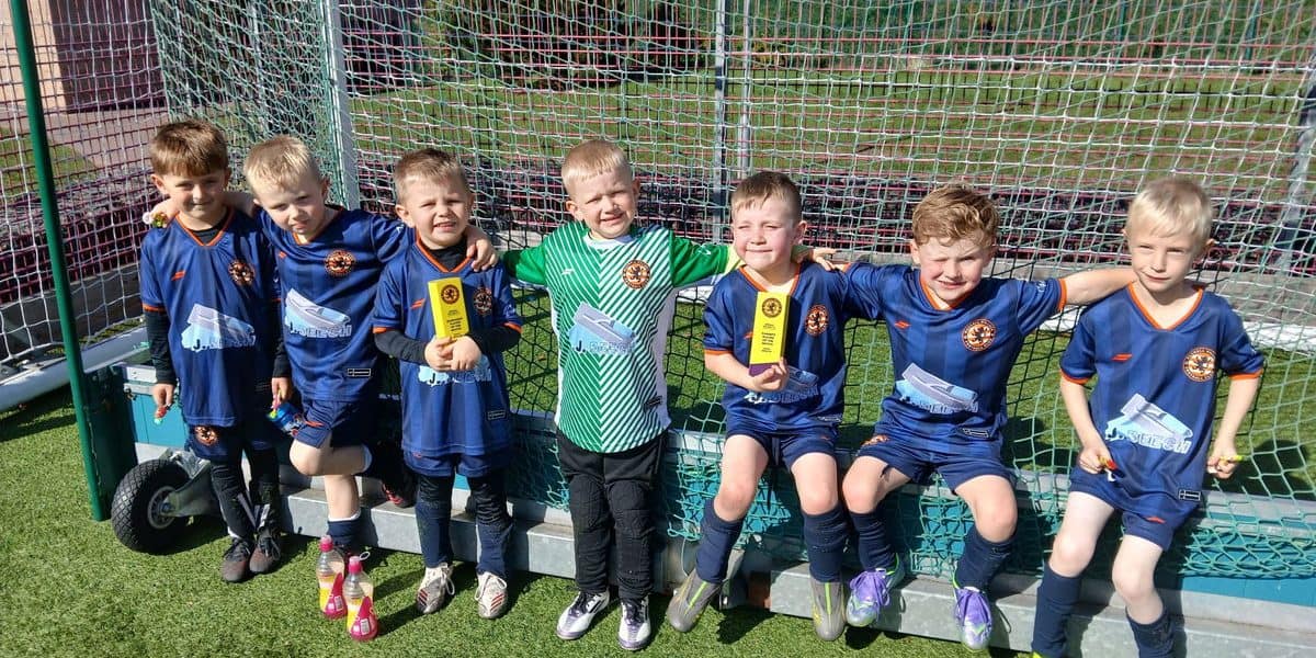 Young boys in Rushall Village football kits standing by goalpost.