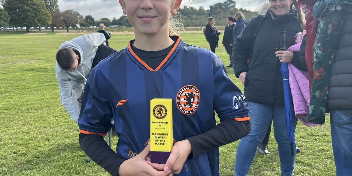 Young football player holding a trophy after a match at Rushall Village Football Club.