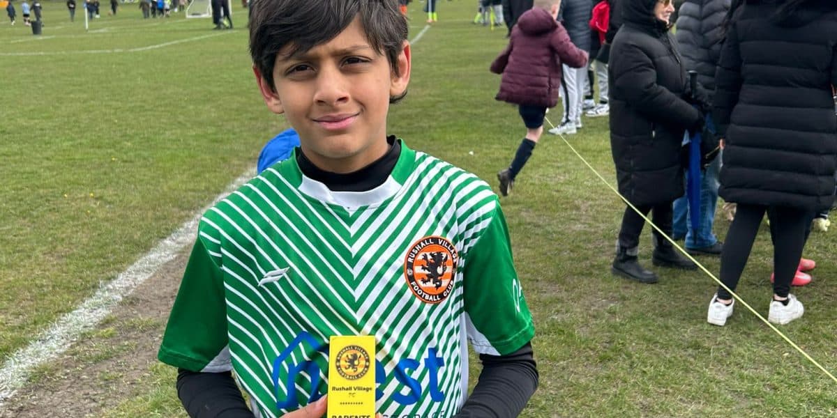 Young footballer holding a trophy after a competitive U11s match at Rushall Village Football Club.