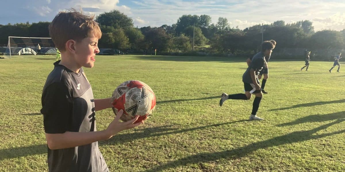 Young players at Rushall Village Football Club enjoying a match on a sunny day.