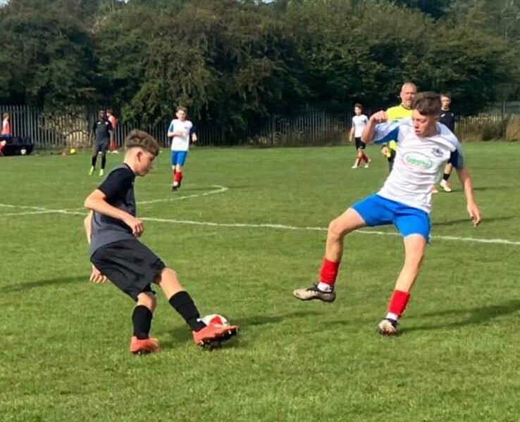 Kids playing football at Rushall Village Football Club on a sunny day.